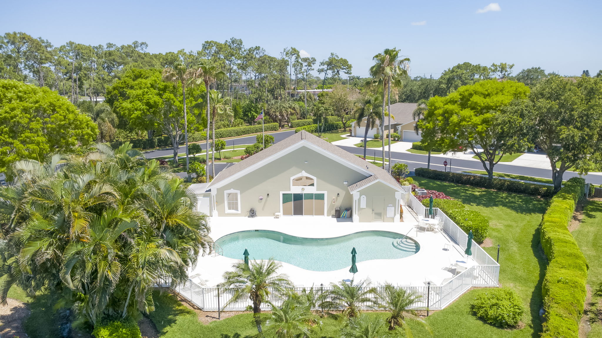 Resort-style community amenities featuring a large, heated swimming pool, expansive paver sun deck, and resident clubhouse.