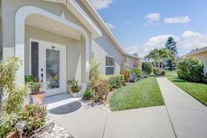 Covered front entryway showcasing a decorative glass-paned door, custom architectural archways, and upgraded exterior lighting.