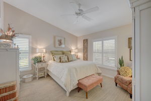 Generously sized primary bedroom suite featuring  large impact windows equipped with custom plantation shutters