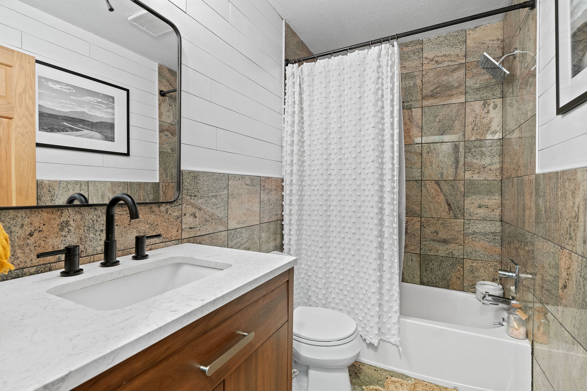 The upper-level full bathroom at 5857 Oneka Lake Boulevard N features a nice wide vanity with a tiled shower surround that goes all the way to the ceiling.