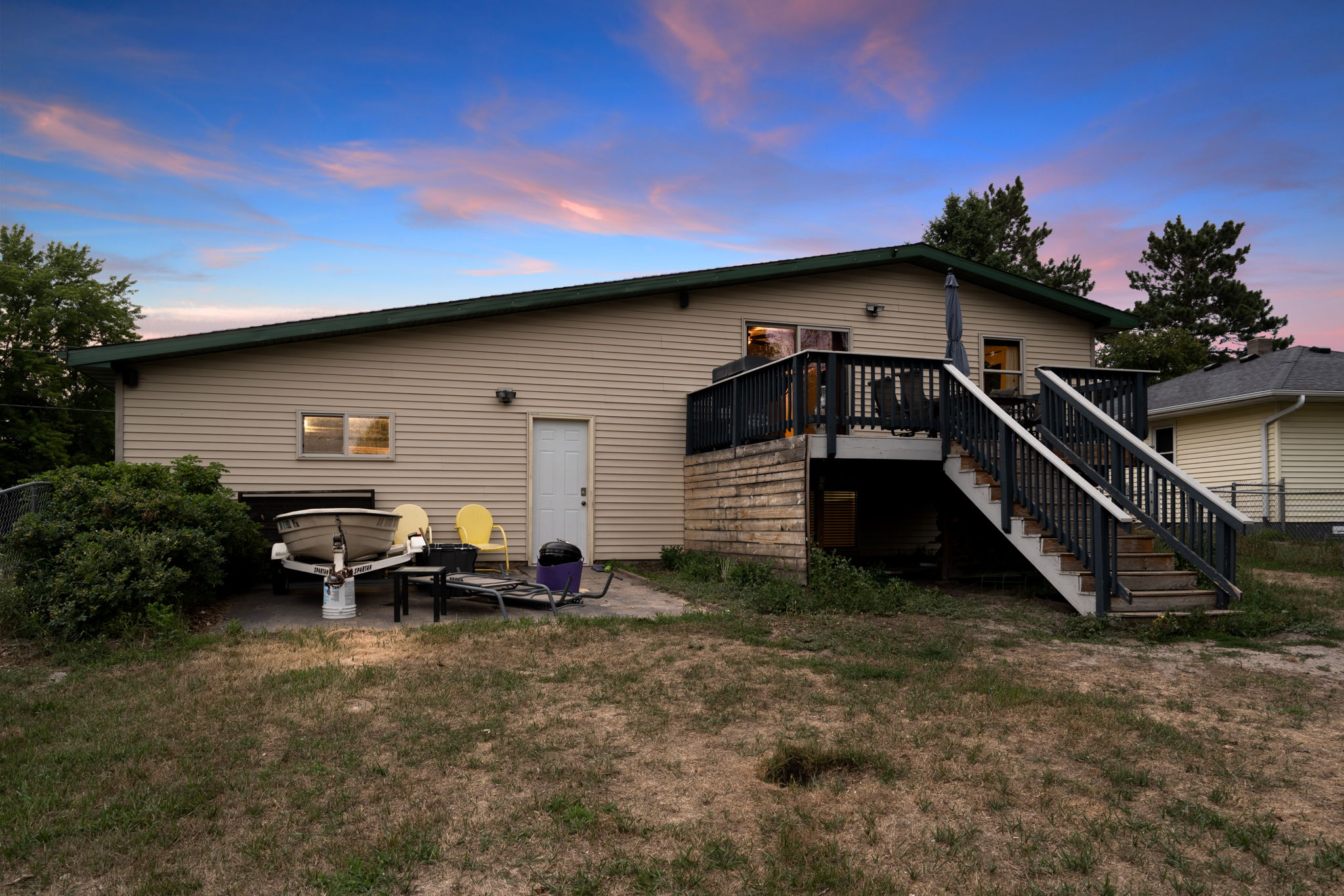 The rear elevation at 5857 Oneka Lake Boulevard N features both an upper-level wooden deck and a ground-level concrete patio, perfect for storing a trailer or boat.