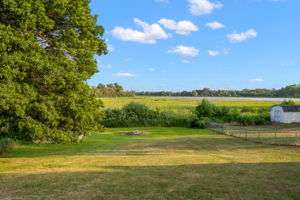 The upper-level deck at 5857 Oneka Lake Boulevard N overlooks the sprawling, fenced-in backyard with Egg Lake in the distance.