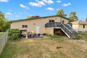 The rear elevation at 5857 Oneka Lake Boulevard N features both an upper-level wooden deck and a ground-level concrete patio, perfect for storing a trailer or boat.