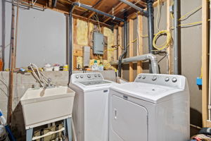 The mechanical room at 5857 Oneka Lake Boulevard N houses the gas forced-air furnace, 40-gallon gas water heater, 100-amp electrical panel on breakers, top-load washer, electric front-load dryer, and large utility sink.