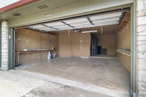 Garage includes additional alcove of storage/work area.