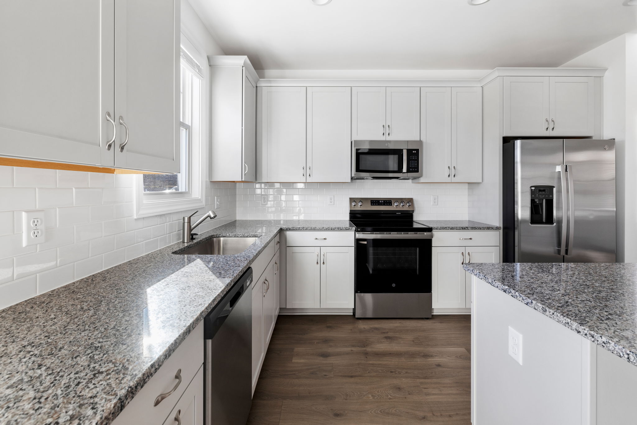 Kitchen features granite counter-tops, GE SS appliances, and a large island.