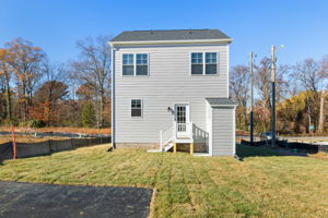 Rear of house with attached storage shed, paved parking, & sodded yard.