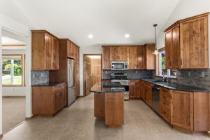 Fully updated kitchen with soft close high-end Alder cabinetry, slab granite counters and an Italian tile backsplash.