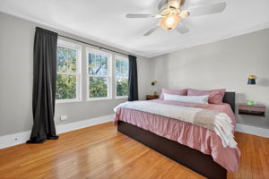Heading upstairs, the primary bedroom has a gorgeous backyard treetop view. Look at the gleaming original hardwoods!