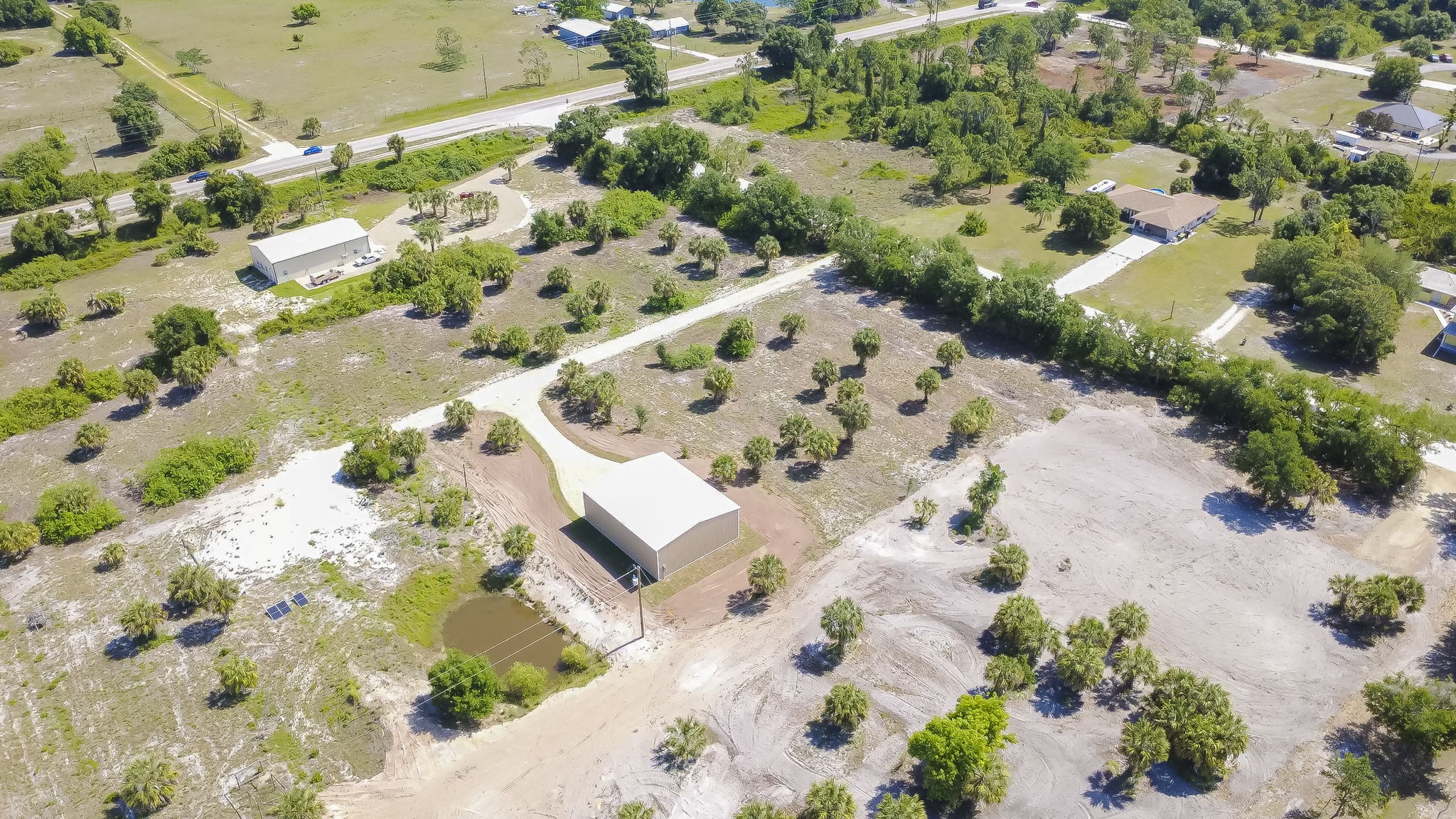 Low aerial shot over the cleared lot emphasizing the generous parking pad and commercial-grade metal siding.