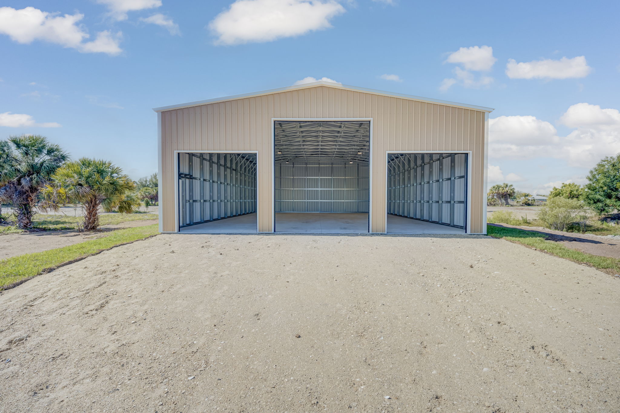 Ground-level front exterior view featuring dual high-clearance commercial roll-up bay doors and impact-resistant steel siding.