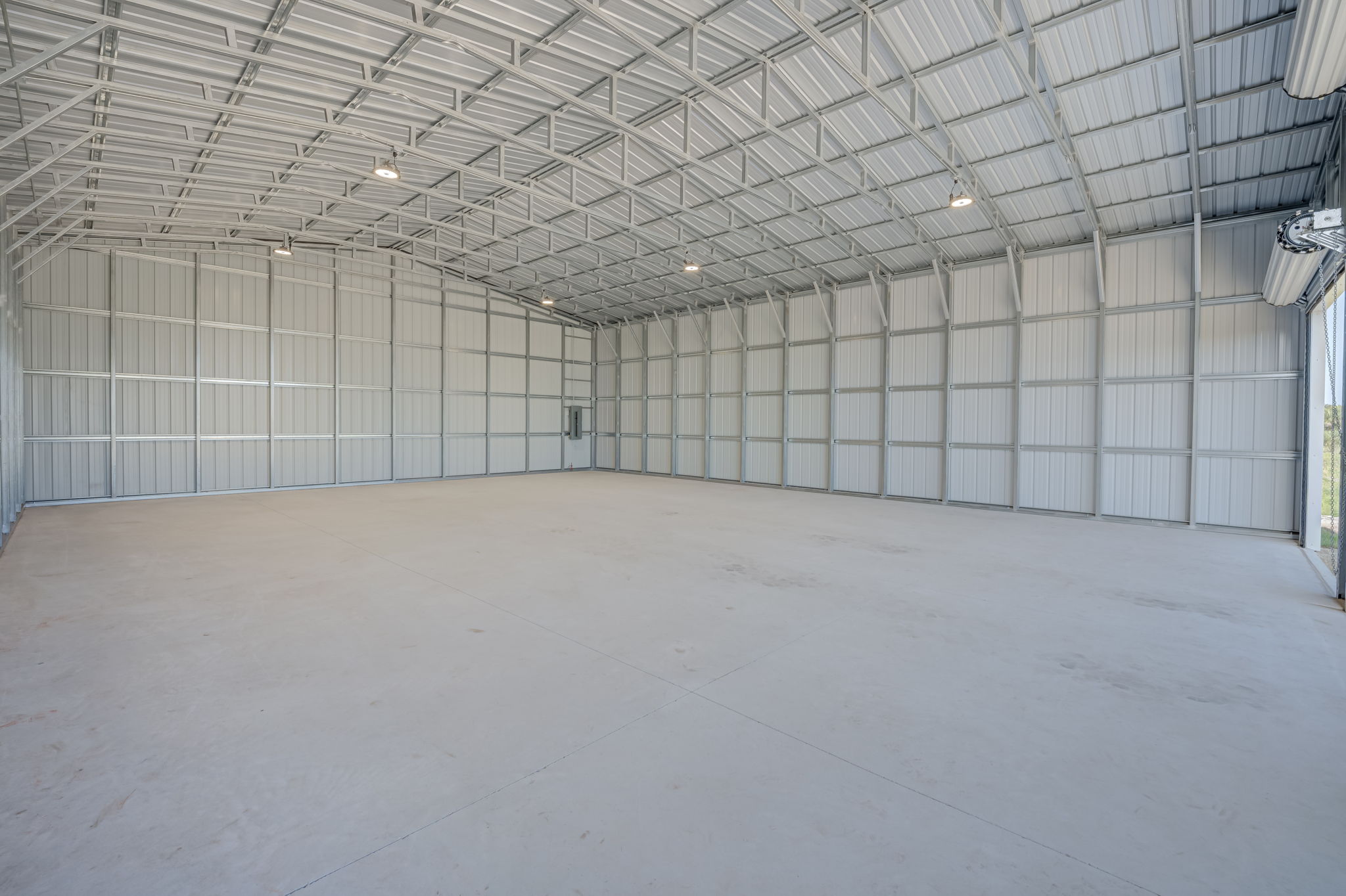 Deep interior shot of the clear-span warehouse showing the reinforced concrete slab flooring and exposed heavy-duty steel framing.