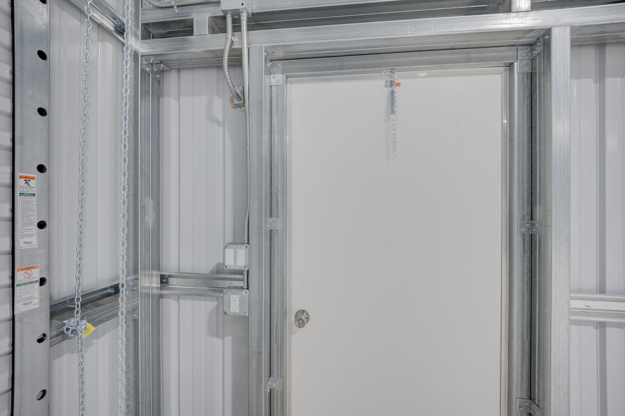 Interior detail highlighting the commercial-grade steel man-door access alongside the heavily insulated structural wall framing.