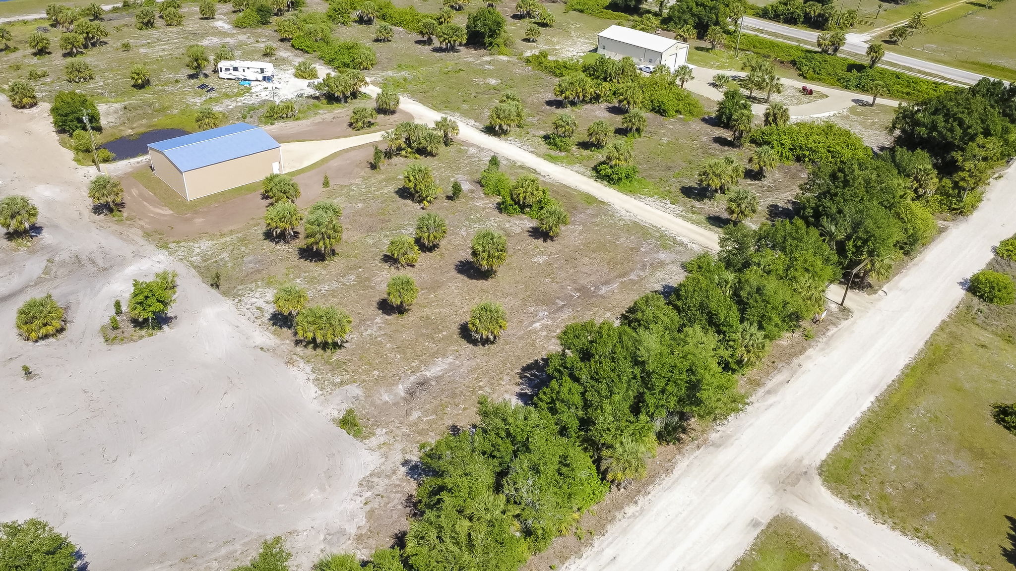Wide aerial angle capturing the strategic placement of the steel structure within the heavily wooded surrounding acreage.