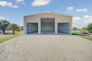 Ground-level front exterior view featuring dual high-clearance commercial roll-up bay doors and impact-resistant steel siding.