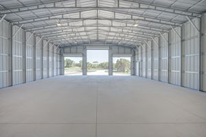 Wide interior view looking out through the open commercial roll-up doors toward the expansive front driveway.