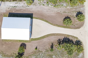 Top-down drone view directly above the metal building highlighting the seamless roof panels and immediate lot clearing.