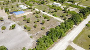 Wide aerial angle capturing the strategic placement of the steel structure within the heavily wooded surrounding acreage.