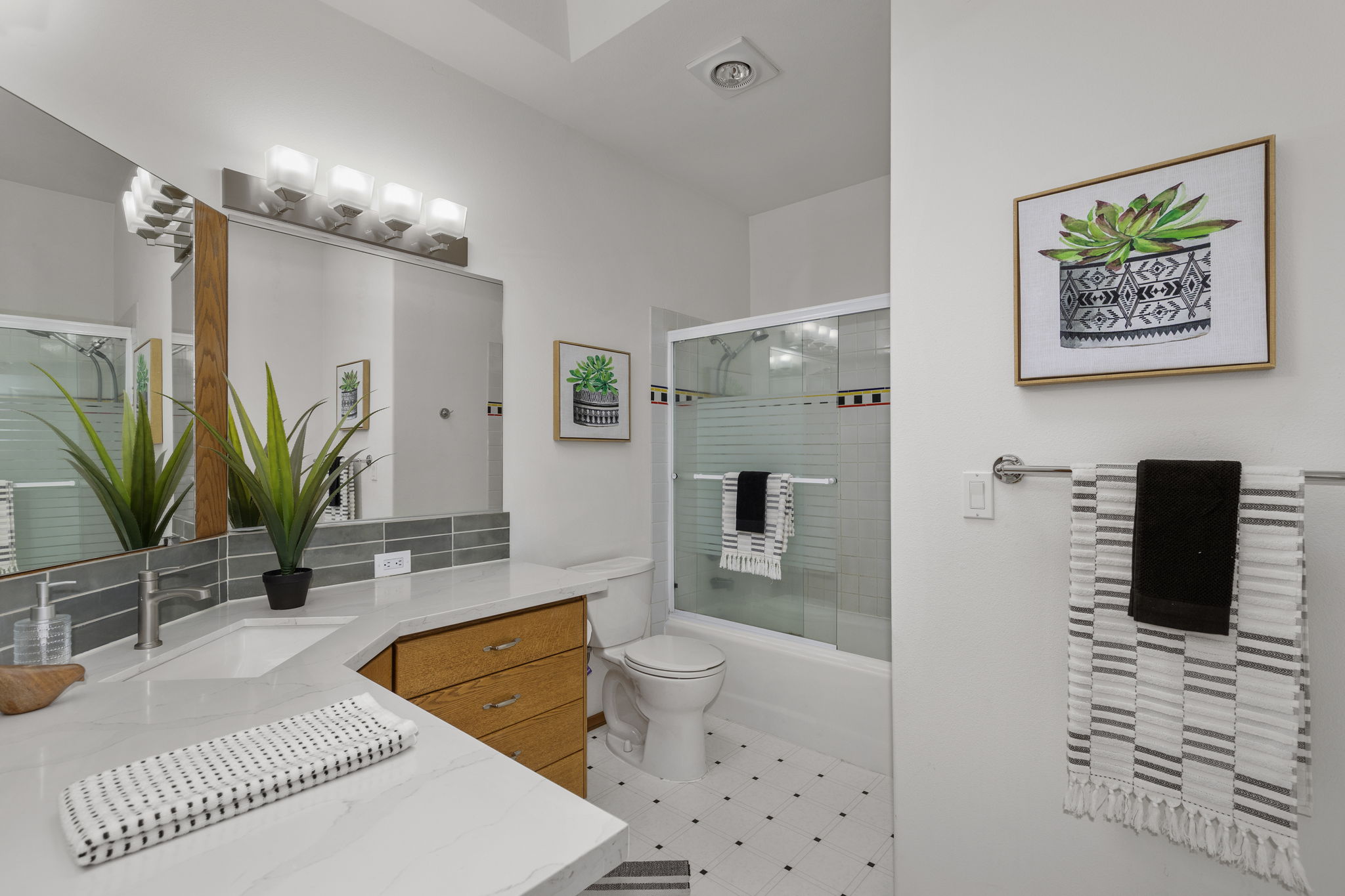 Upper level shared bath with new quartz countertops, backsplash and lighting! There is a lovely skylight in this bathroom too!