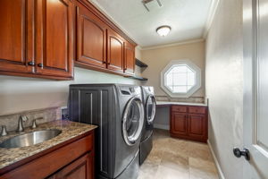 Laundry room with sink, abundant cabinetry, & view