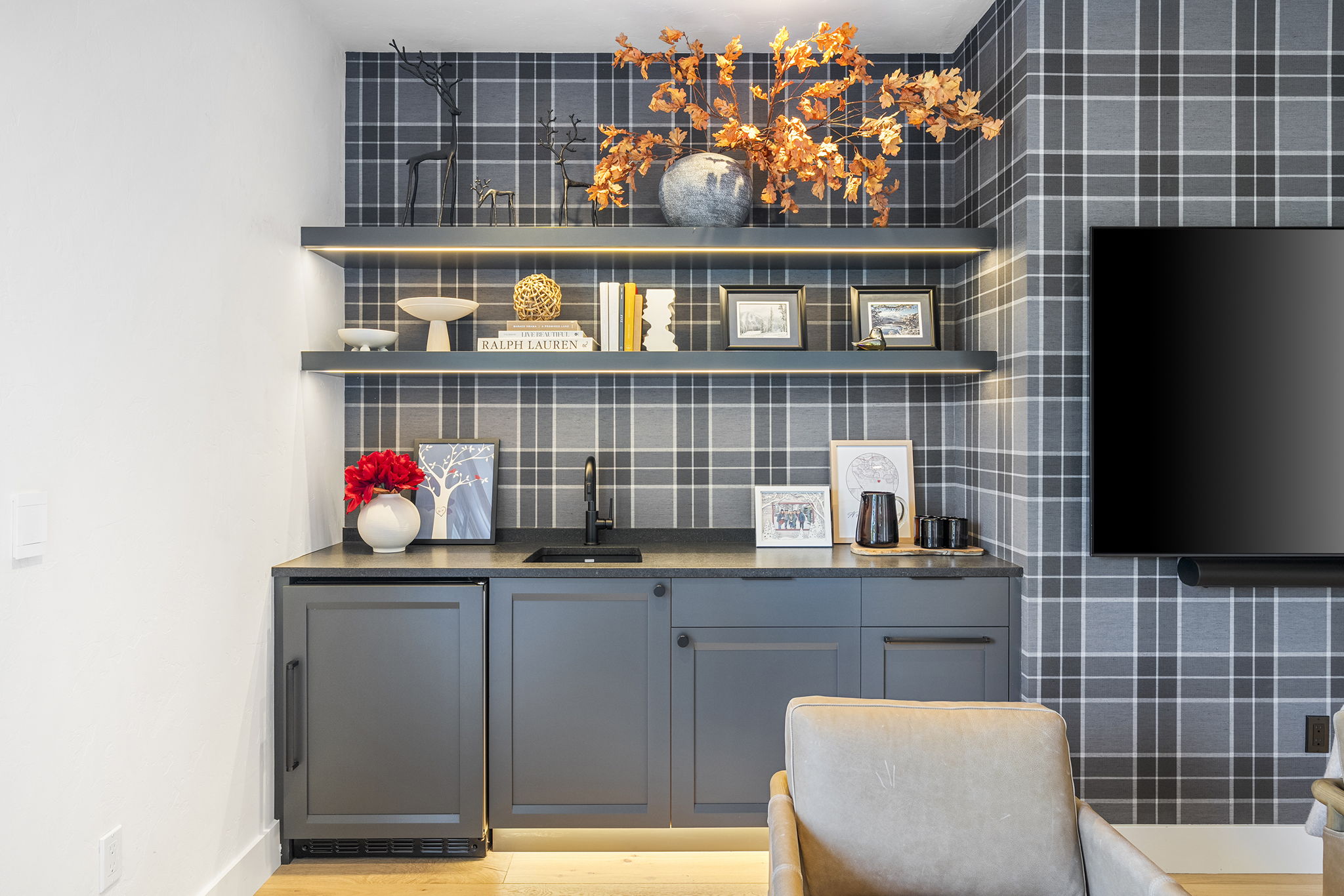 Linen wall covering flanks the wet bar and beverage fridge