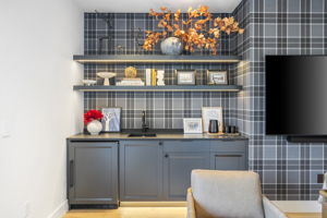 Linen wall covering flanks the wet bar and beverage fridge