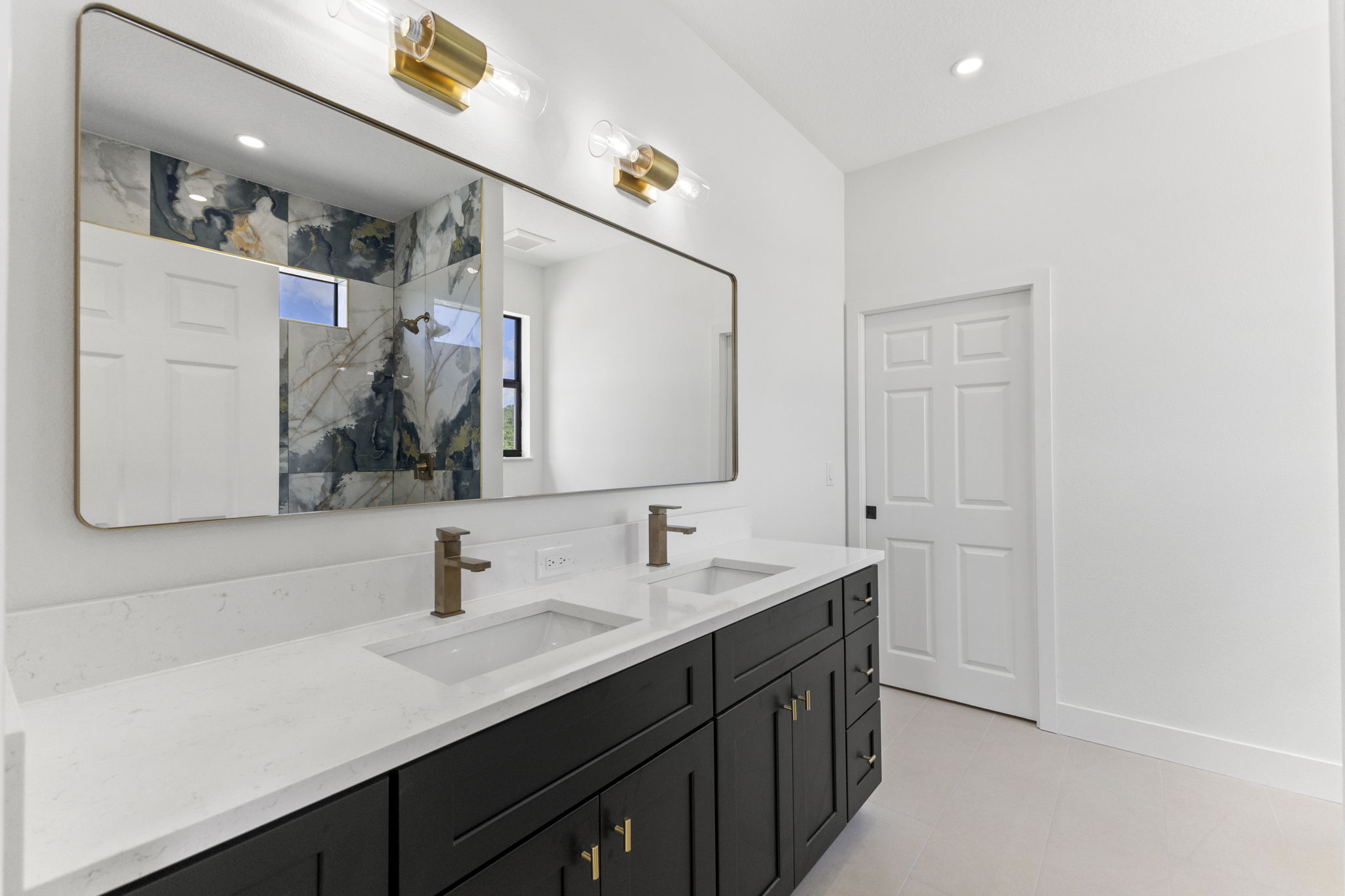 Primary bathroom with dual vanities and a tiled shower surround at Latitudes in the Park, Pinellas Park FL