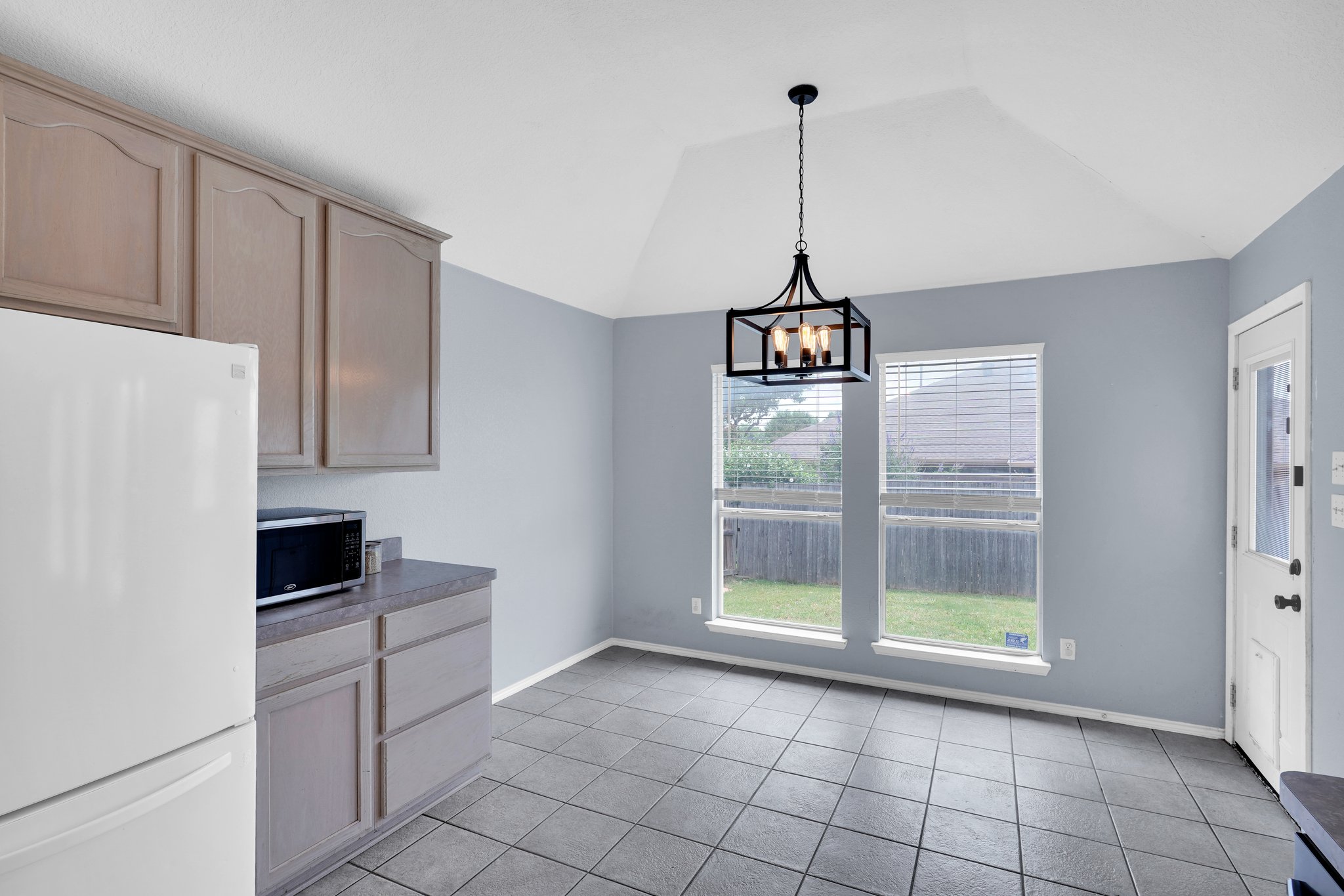 Plentiful natural-toned cabinetry provides ample storage while connected to a dining space