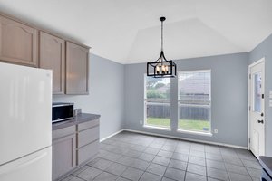 Plentiful natural-toned cabinetry provides ample storage while connected to a dining space
