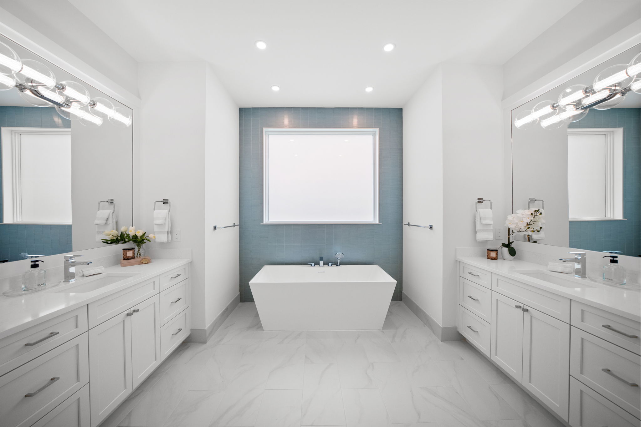 Spacious primary bath featuring a freestanding soaking tub set against a decorative glass tile accent wall