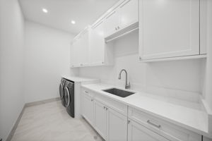Expansive laundry room with plenty of countertop space, upper and lower cabinetry, and utility sink