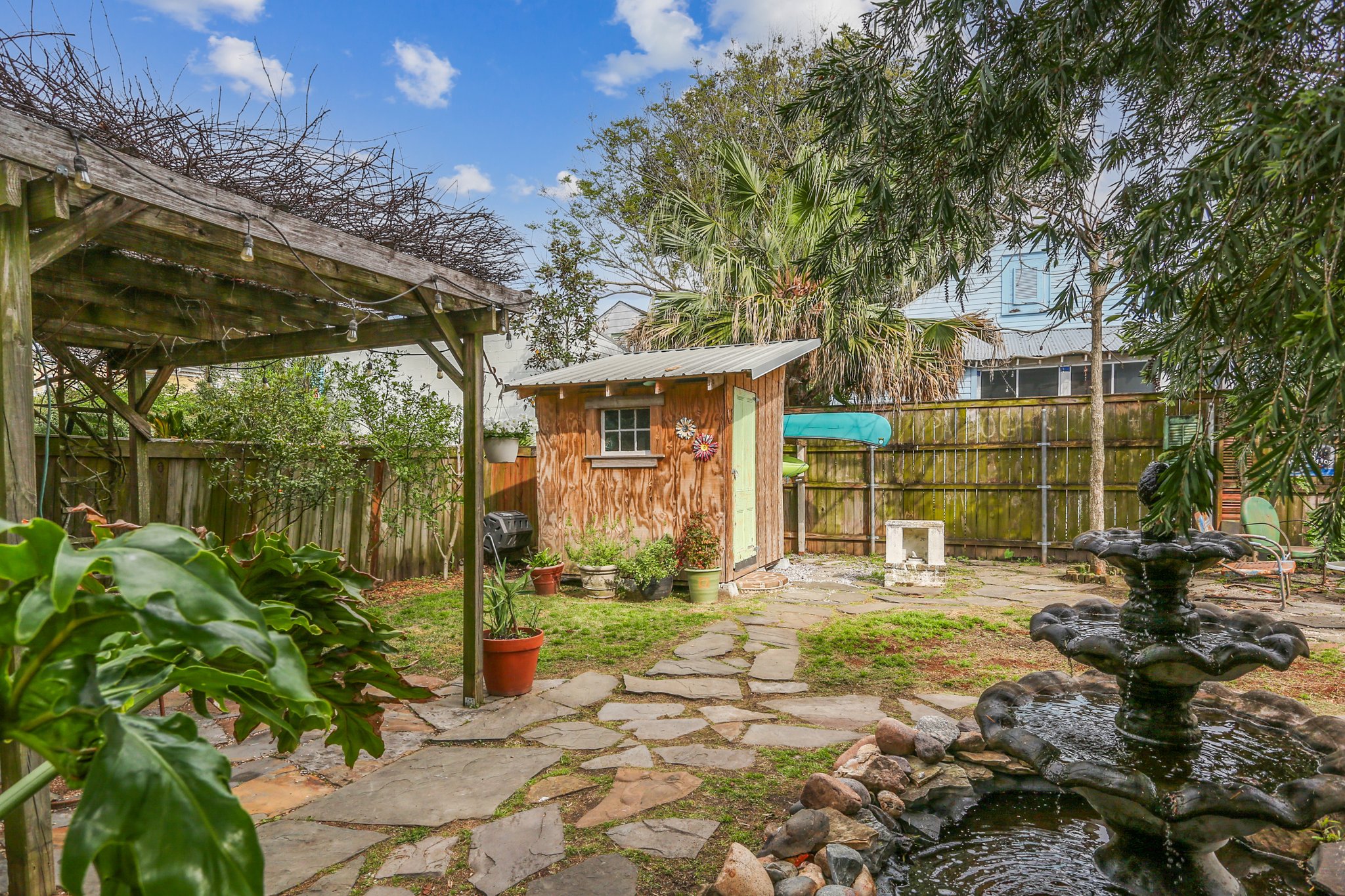 Covered seating under a vine-shaded pergola is ready for entertaining guests.