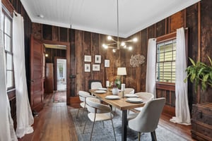 This space is warm and rustic compared to the sophisticated and cool blue of the first bedroom. The white painted  ceilings and champagne bronze chandelier offer a nice contrast with the barge board walls and hardwood floors