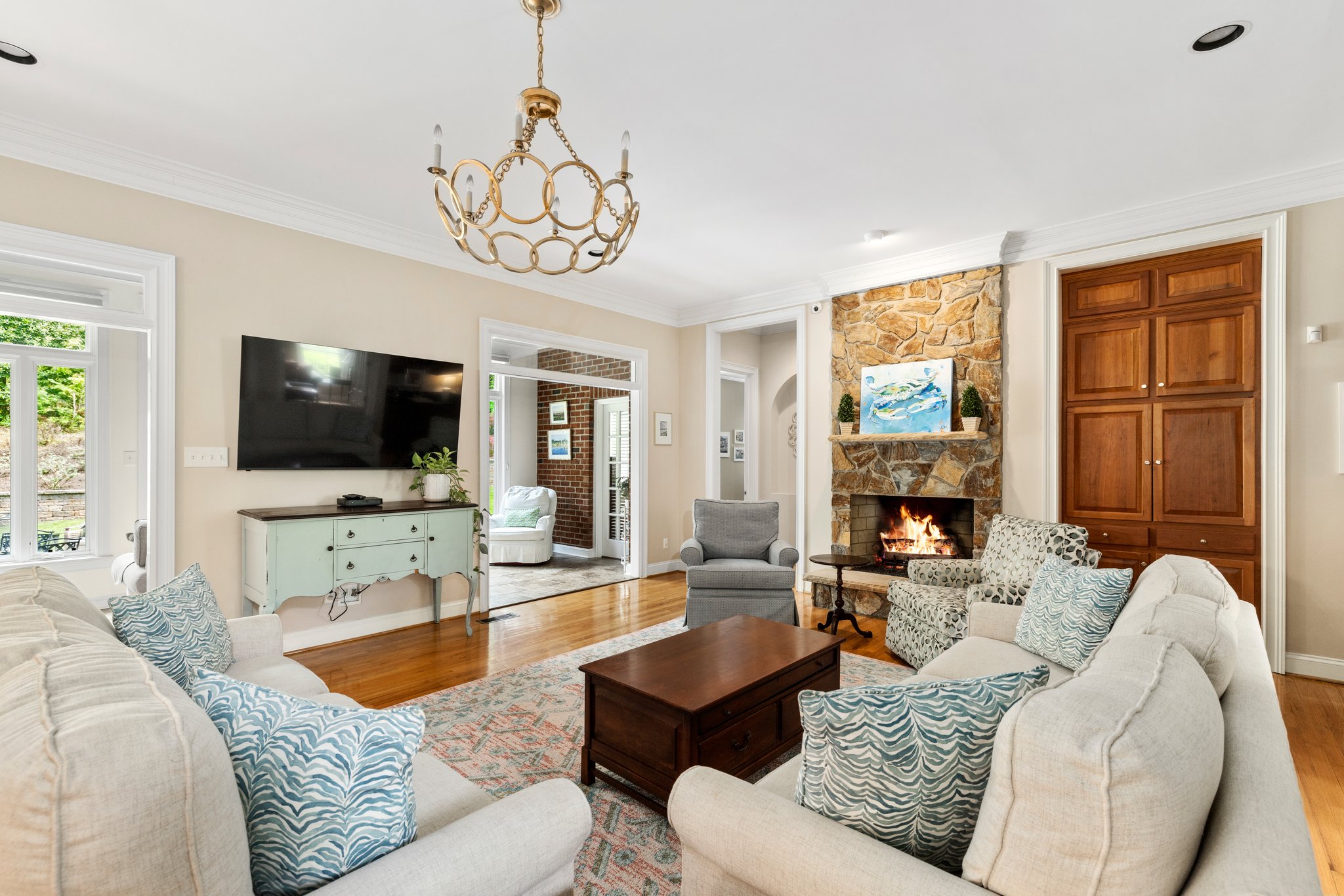 Spacious family room with raised hearth gas fireplace with stone mantle, built-in media center, chandelier, and recessed lighting.