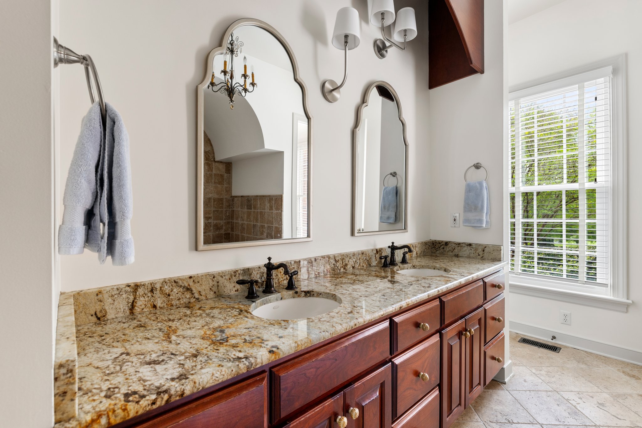 Spa-like primary bathroom with dual vanities with granite countertops and undermount sinks.
