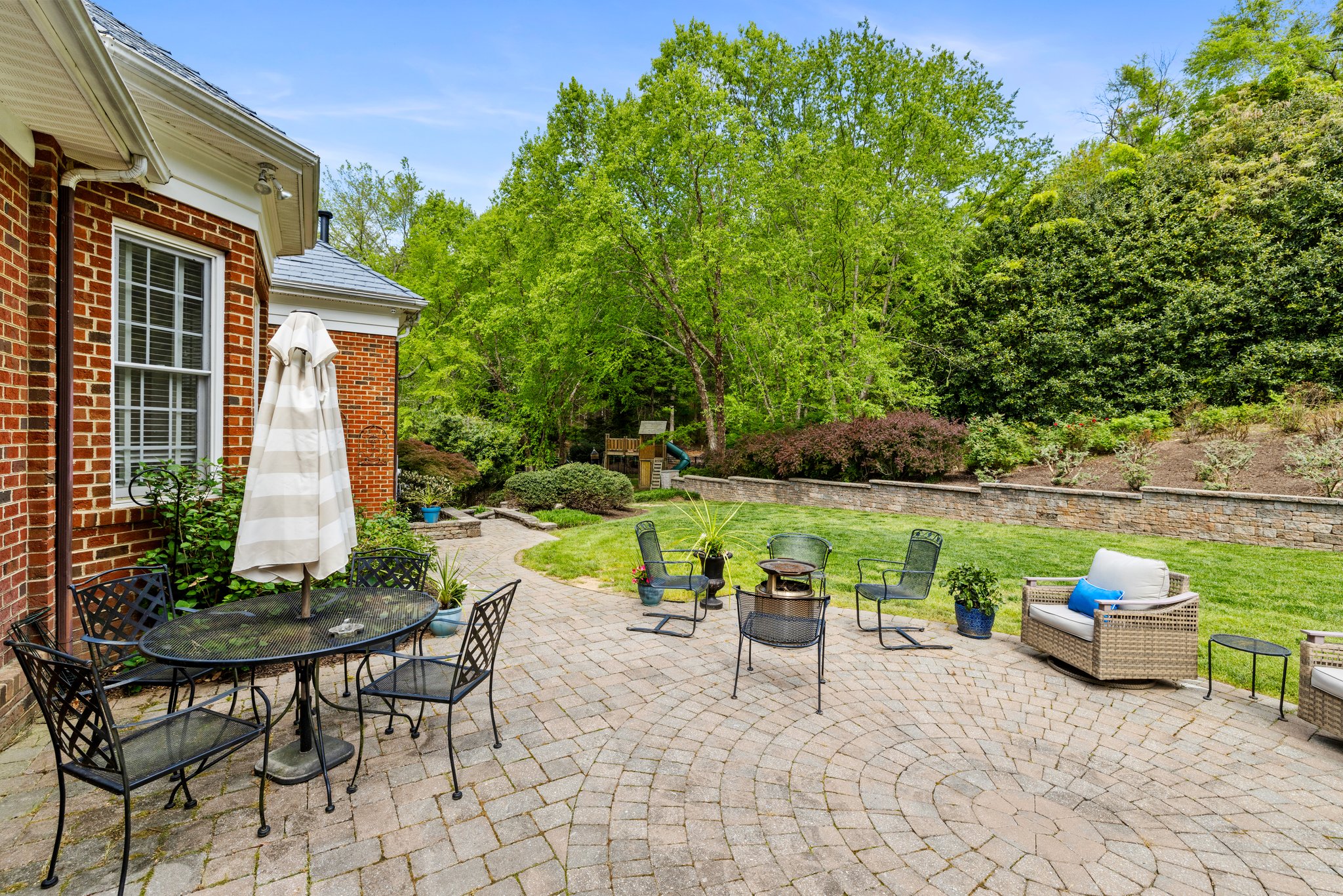 Massive paver patio that opens to a private backyard with paver stone retaining wall.
