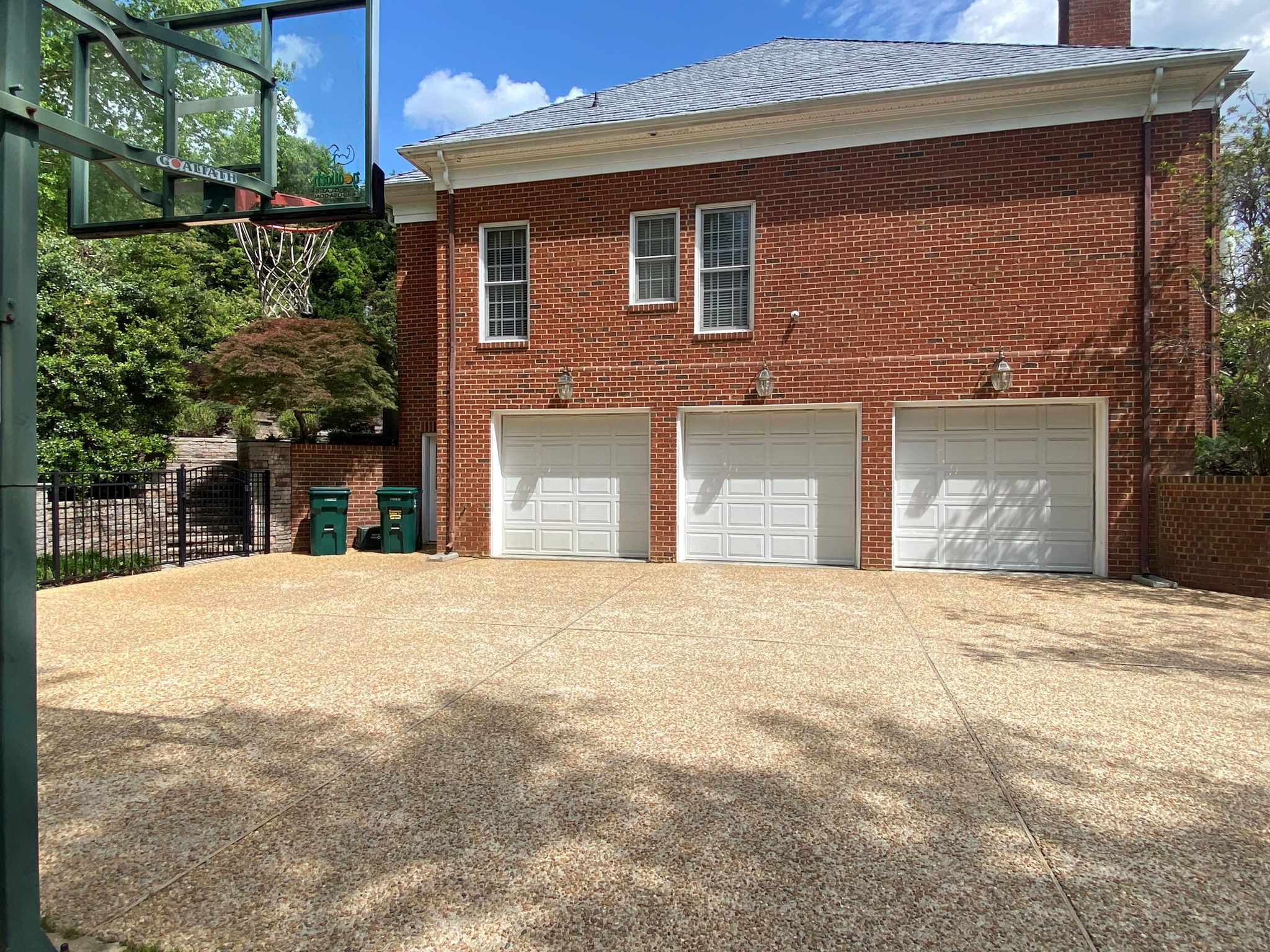 Huge 3 car garage with space for storage with a large aggregate driveway for parking multiple cars or enjoying a game of pick up basketball.