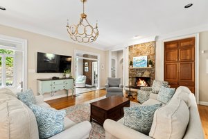 Spacious family room with raised hearth gas fireplace with stone mantle, built-in media center, chandelier, and recessed lighting.