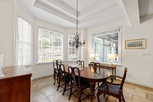 Sunny breakfast room with bay window, chandelier, and tray ceiling.