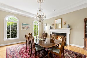 Formal dining room with gas fireplace, tray ceiling, crystal chandelier, and arched windows.
