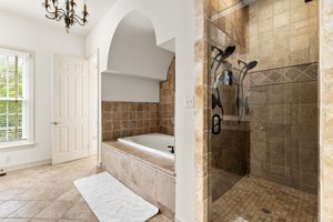 Primary bath has jetted tub and huge shower with dual heads and shower bench.
