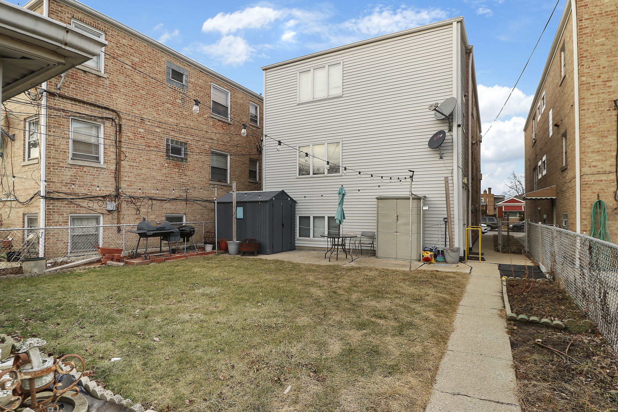 Fenced backyard with patio and two storage sheds