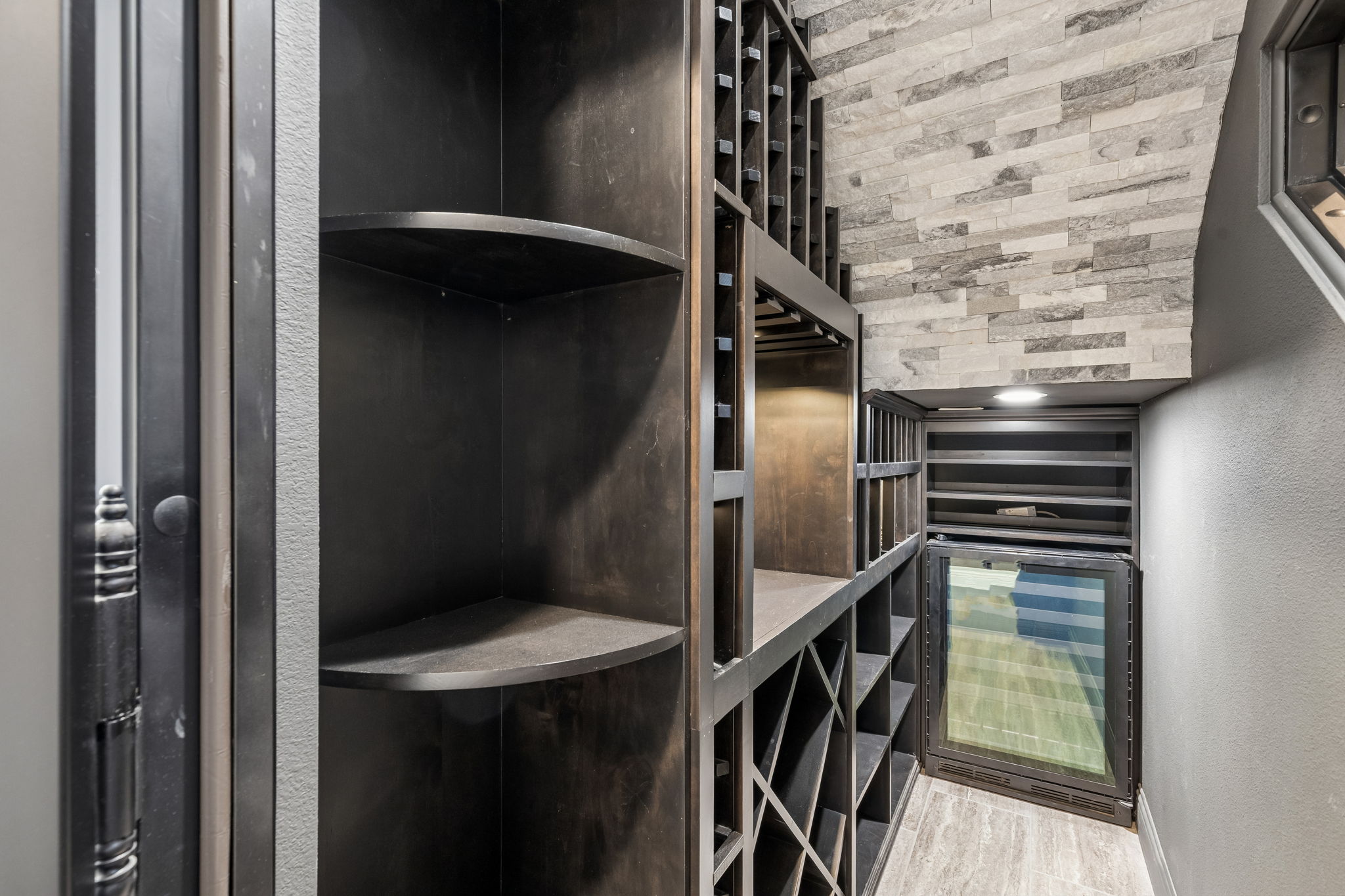 The custom 251+ bottle wine grotto features integrated bottle and stemware storage, an illuminated display ledge and built-in wine refrigerator