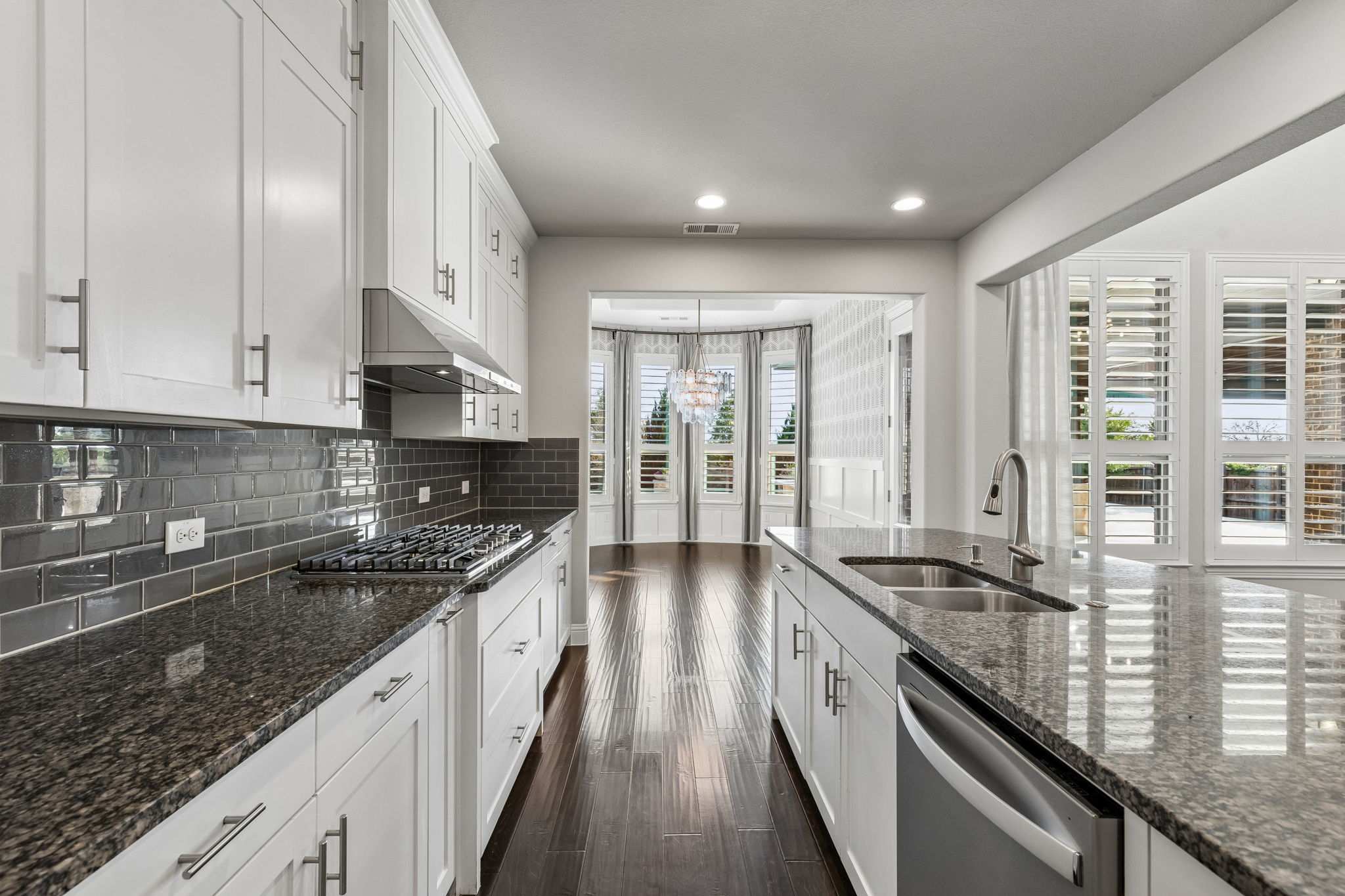 The kitchen’s granite surfaces, ceiling-height cabinetry and 2026 gas cooktop flow seamlessly into the designer-finished dining room beyond