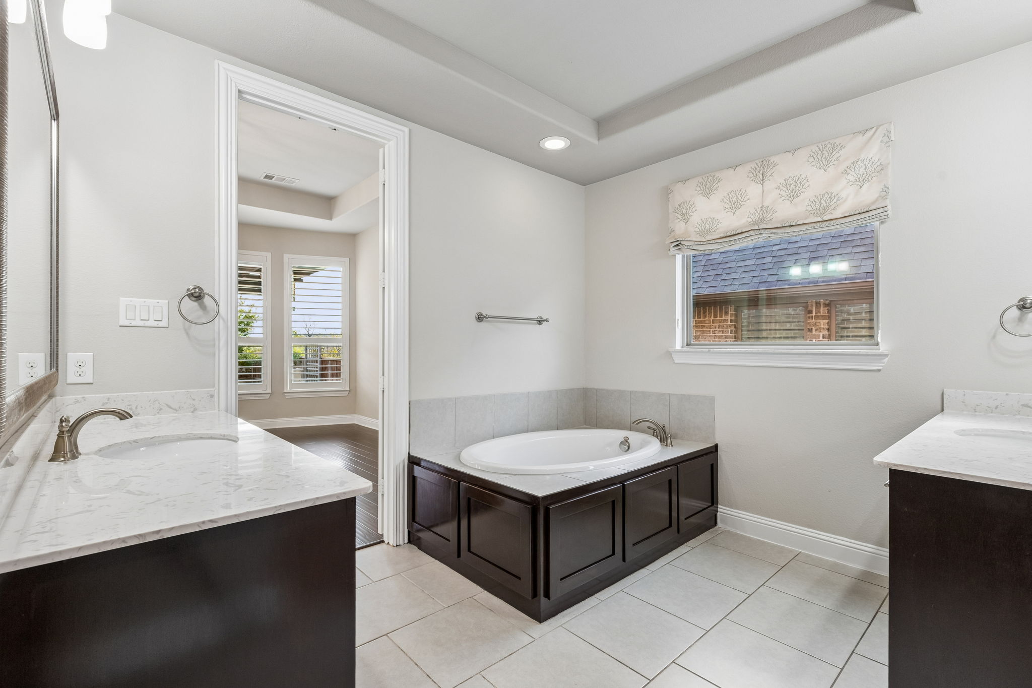 Dual vanities & garden tub, creating generous space within the primary bath. Window does have light filtering roller shade under the roman shade.