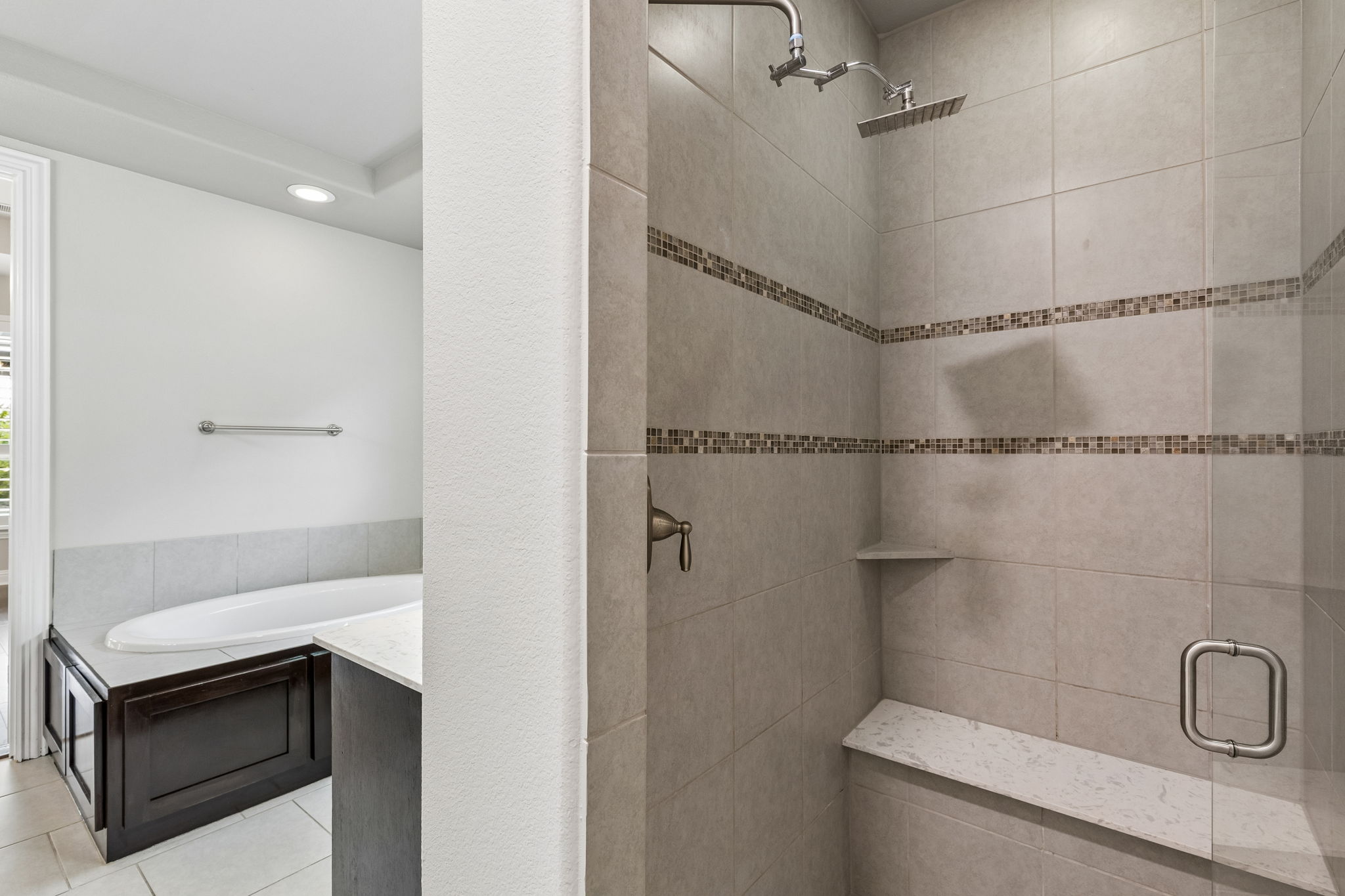 The primary bath features a spacious walk-in tiled shower with bench seating and frameless glass.