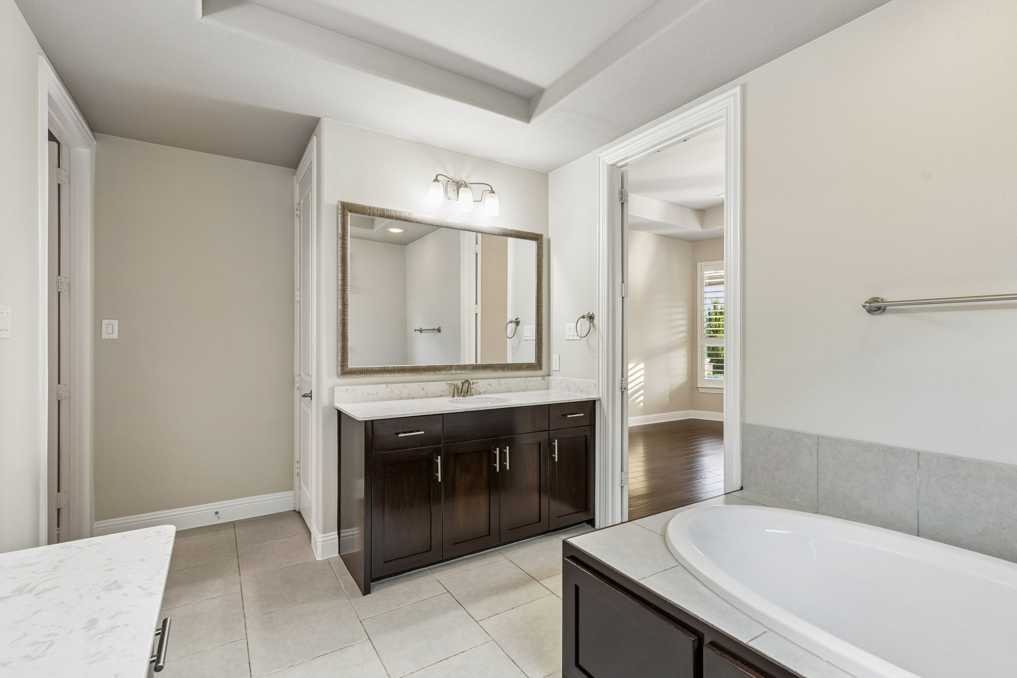 Dual vanities & garden tub, creating generous space within the primary bath. Window does have light filtering roller shade under the roman shade.