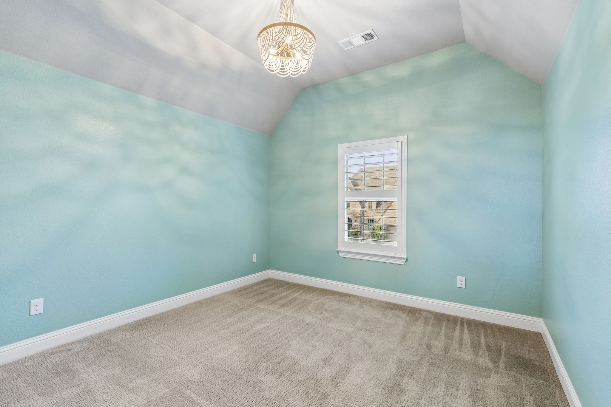 Vaulted ceilings, plantation shutters and a designer light fixture add character to this upstairs secondary bedroom.