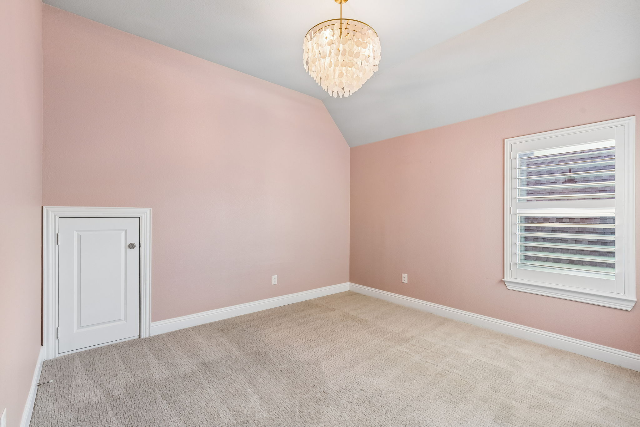 Vaulted ceilings, plantation shutters and a designer light fixture add character to this upstairs secondary bedroom.
