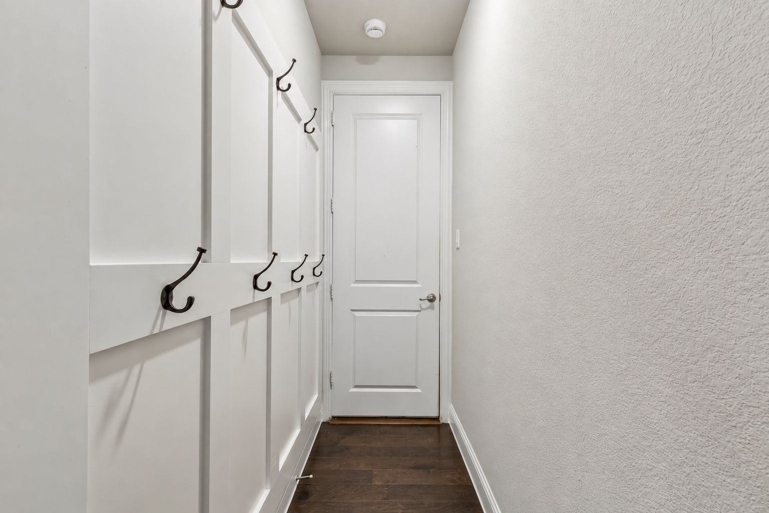 A dedicated mudroom/drop zone offers built-in board-and-batten detail with multiple hooks, creating a convenient everyday landing space just off the garage